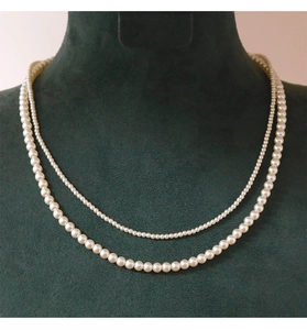 Detail of double-layer pearl necklace with small and large beads on green velvet stand