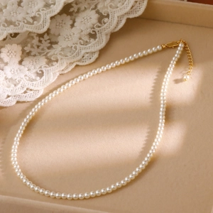 Elegant 2mm white pearl choker necklace with gold adjustable lobster clasp on jewelry tray