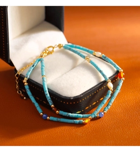 Detalle de pulsera vintage de turquesa y perlas con cierre dorado sobre estuche de lujo