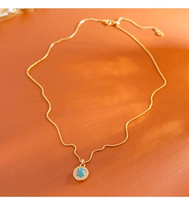 Détail d'un collier vintage doré avec pendentif turquoise entouré de zircons étincelants