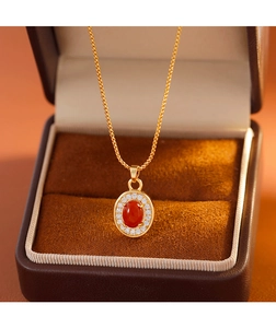 Détail d'un pendentif en agate rouge avec halo de zircon et chaîne dorée dans son écrin luxe