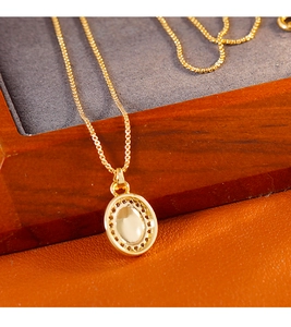 Vue macro du pendentif vintage plaqué or avec pierre blanche sur boîte en bois
