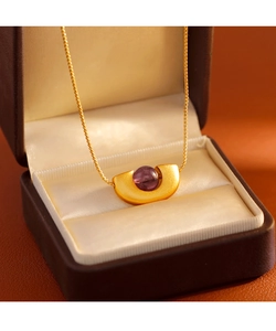 Vue macro détaillée du collier en or mat orné d'une pierre précieuse violette centrale