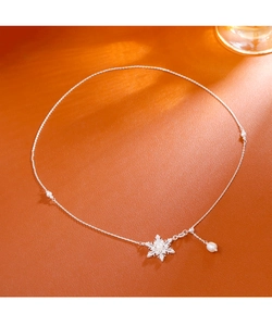 Dettaglio di elegante collana a fiocco di neve con perle su superficie arancione calda