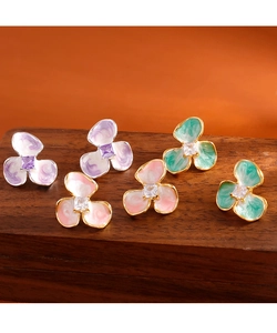Dettaglio degli orecchini a fiore in smalto viola, rosa e verde menta con zircone quadrato