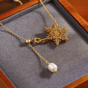 Elegante collana a fiocco di neve dorata con pendente di perla in una scatola di lusso