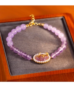 Detalle de pulsera de cuentas moradas con colgante de rosa dorada e incrustación de perlas