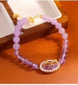 Vista macro de pulsera de amatista con colgante de ciervo dorado y detalles de perlas