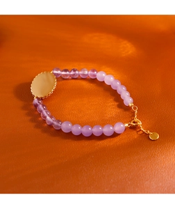 Detalle macro de pulsera de amatista natural con colgante floral dorado y cierre de langosta