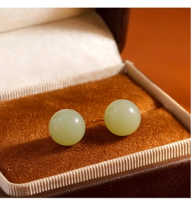 Vue macro de boucles d'oreilles en jade Hetian avec un lustre chaud dans un écrin