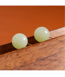 Gros plan de boucles d'oreilles minimalistes en jade vert sur un support en bois texturé