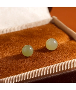 Vue macro de boucles d'oreilles minimalistes en jade Hetian dans un écrin en velours brun