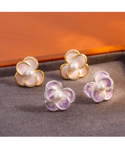 Macro detail of enamel flower stud earrings with central pearls and sparkling rhinestones