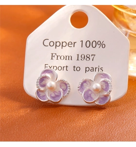 Macro detail of enamel flower earrings with pearls and crystals on premium copper base