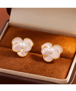 Close-up of pink enamel flower earrings with pearls and zircon on gold metal base