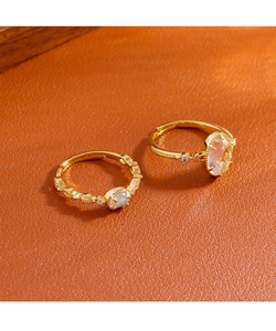 Detail of adjustable gold rings featuring an oval opal and a clear faceted crystal stone