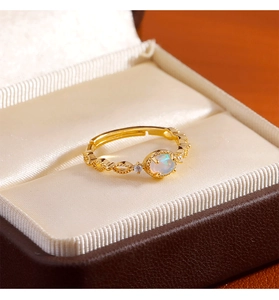 Detail of gold opal ring with open adjustable band and hollow woven texture design