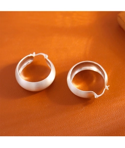 Gros plan de créoles en argent sterling S925 avec finition mate brossée sur du cuir