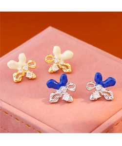 Detalle macro de pendientes de lazo esmaltados con circonitas en joyero de terciopelo rosa