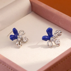 Pendientes de flores en esmalte azul con cristales en un joyero rosa de estilo elegante