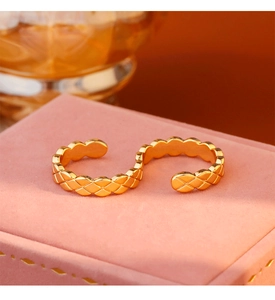 Makroansicht des goldenen Rings mit Rautenmuster auf rosa Samt bei warmem Licht