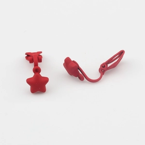 Detail van matte rode ster clip-on oorbellen met een gladde gespoten metalen afwerking