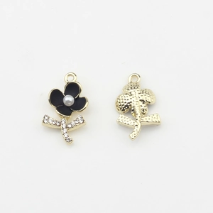 Détail de pendentif fleur en émail noir, perle centrale et revers texturé doré brillant