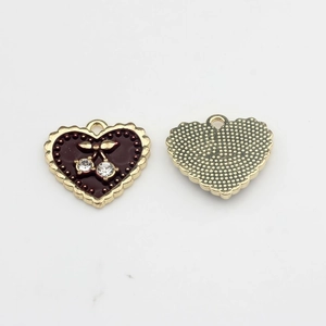 Detail of red enamel heart charms with cherry rhinestones and textured golden back
