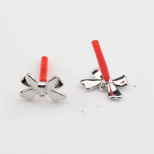 Close-up of silver bow jewelry pendants with small rings and red protective needle caps