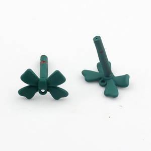 Detailed macro view of dark green matte bow charms for DIY jewelry and crafts making