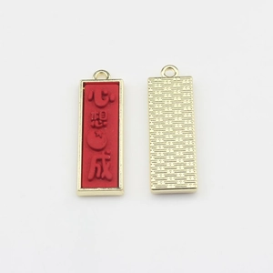 Vue macro d'un pendentif en alliage rouge avec caractères chinois gaufrés et fini doré