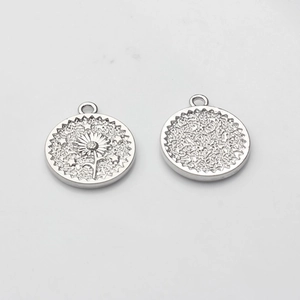 Detail view of round coin pendant with sunflower relief and textured back in silver finish