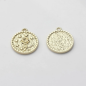 Macro shot of gold-plated round pendants with embossed rose and hammered metal texture