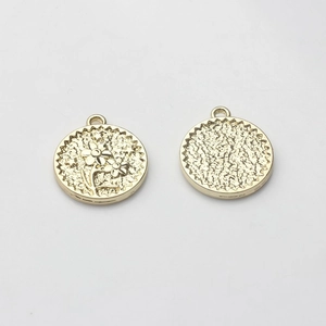 Detailed view of gold round flower coin charms with embossed texture for DIY jewelry making