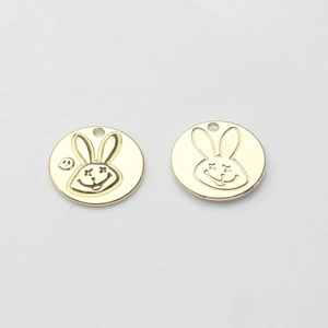 Détail de breloques lapin dorées avec gravure yeux en X pour création de bijoux DIY
