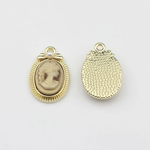 Detail of vintage gold alloy oval pendant with lady relief and white faux pearl accent