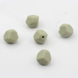 Detalle de cinco cuentas facetadas de silicona verde salvia para la creación de joyas DIY