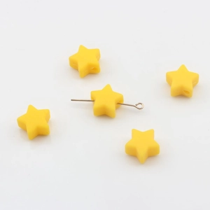 Gros plan détaillé de perles d'étoiles en silicone jaune montrant le trou de perçage