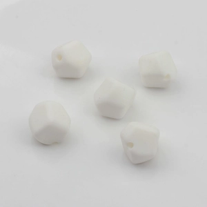 Primer plano de cinco cuentas geométricas de silicona blanca con agujeros para joyería DIY