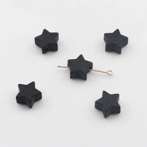 Gros plan sur des perles étoiles en silicone noir de 14mm avec perçage pour bijoux
