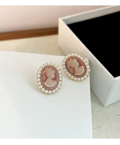Macro shot of vintage cameo earrings with pink relief and white pearl border detail