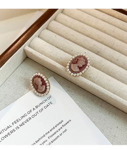 Detailed close-up of vintage cameo earrings with pink portrait and pearl borders