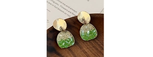 Gros plan de boucles d'oreilles dorées brossées avec cristaux vert émeraude et champagne