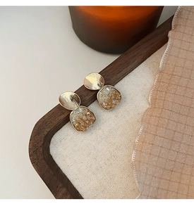 Détails de la texture en métal brossé doré et cristaux d'ambre sur boucles