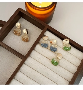 Vue détaillée des boucles d'oreilles dorées brossées avec pendentifs en cristal résine