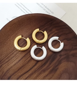 Detalle de pendientes de aro mate en oro y plata sobre una bandeja de madera