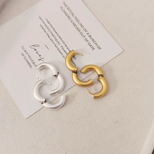 Pendientes de aro en forma de C mate dorado y plateado sobre elegante papel vintage