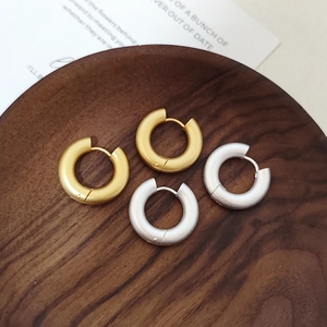 Pendientes de aro gruesos en oro y plata mate sobre una bandeja de madera de estilo vintage