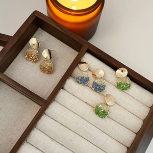 Élégantes boucles d'oreilles dorées avec cristaux oranges, bleus et verts dans leur boîte