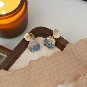 Boucles d'oreilles dorées brossées avec pendentifs en cristal orange sur présentoir